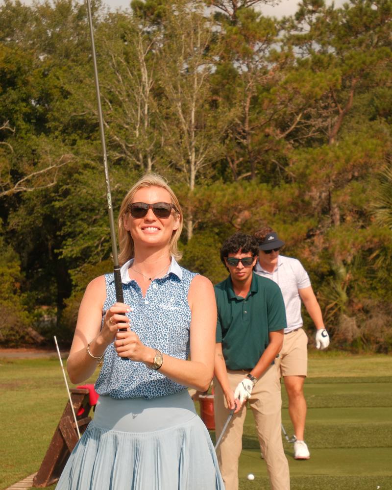 Three golfers on a practice tee wearing Rheos sunglasses